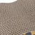 Nahaufnahme einer Wellpappestruktur, braun mit sichtbarem Muster. Unterer Rand zeigt ein gelbes und graues Tarnmuster.