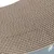 Gros plan sur une surface en carton ondulé, motif en nid d’abeille visible. Bord inférieur avec partie grise et motifs de fleurs blanches.