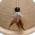 Toy made of sisal rope with wooden base, black ball and brown feathers.