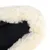 Gros plan sur le bord d’un coussin pour animal en tissu noir avec rebord en fausse fourrure blanche.