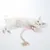 Weisse Katze spielt mit einem rosa Spielzeug mit langem Seil und Quaste. Produkt zeigt Nutzung eines Katzenspielzeugs.