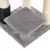 Plateforme grise en tissu avec poteaux recouverts de sisal et brosse noire à picots, base d’un arbre à chat visible.