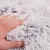 Close-up de uma mão a tocar em material macio e felpudo de cor branco-cinzento.