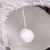 Vista interior de uma toca macia com bola de pelúcia branca pendurada por um cordão, adequada como brinquedo ou refúgio.