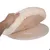 Coussin rond beige à bordure crème en tissu et fausse fourrure, soulevé par une main, posé sur une base circulaire en bois avec bandes auto-agrippantes visibles.