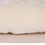 Gros plan sur un coussin en tissu peluche beige posé sur une base en bois clair, sans marque visible.