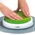 Hands pressing on green sieve in white base with grey mat, product by Catit. Demonstration of product use.