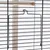 Metal bracket for birdcage, attached to bars with wooden perch in the background.