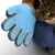 Blauer Pflegehandschuh mit Noppen zur Fellpflege, neben einer Katze. Zeigt Funktion des Handschuhs beim Entfernen von Tierhaaren.