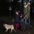 Person and child walking a dog on an extendable lead at night, demonstrating use of the retractable leash outdoors in low light conditions.