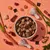 Bowl of cubed pet food surrounded by raw meat pieces, carrot slices, whole carrots, rice grains and seaweed, showing visible ingredients used in the product.