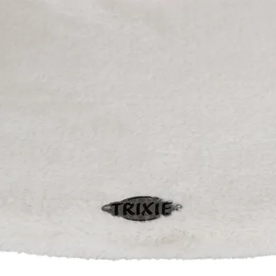 Surface en tissu blanc avec une plaque métallique portant l’inscription TRIXIE visible au centre bas de l’image.