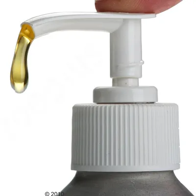 Doseador de plástico branco a libertar uma gota de líquido amarelo, visto de perto. Tampa com superfície canelada visível.