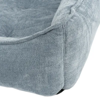 Dettaglio di una cuccia imbottita per animali in tessuto grigio, con bordo rialzato e superficie morbida visibile.