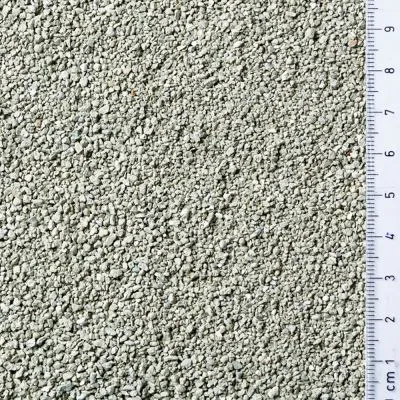 Detailní pohled na zrnitý materiál světlé barvy s pravítkem v centimetrech pro určení velikosti zrn od 0 do 9 cm.