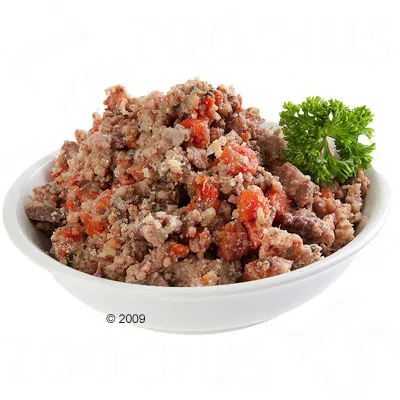Ciotola bianca con alimento umido per animali, composto da pezzi di carne e verdure visibili, decorato con un rametto di prezzemolo.