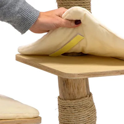Mano che mostra un cuscino rimovibile e imbottito con chiusura a strappo su una piattaforma in legno di un tiragraffi.