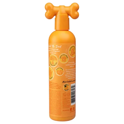 Flacone arancione con tappo a forma di osso, testo visibile in inglese: 'Never tested on animals', simboli di limone, zampa, aloe vera, scritta 'Made in the USA'.