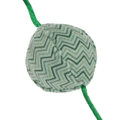 Textilná loptička so zeleným cikcakovým vzorom, prevlečená zelenou šnúrkou. Materiál: textil a šnúrka.