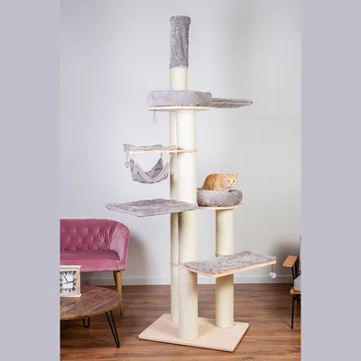 Rascador para gatos de varios niveles con plataformas, hamaca y cama acolchada gris claro. Un gato naranja está tumbado en una de las camas superiores.