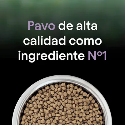 Pavo de alta calidad como ingrediente Nº1, texto sobre un cuenco metálico lleno de croquetas marrones para mascotas.