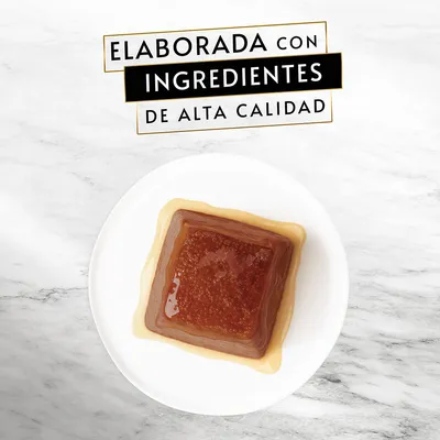 Texto: Elaborada con ingredientes de alta calidad. Comida húmeda para mascotas en forma de bloque cuadrado sobre un plato blanco.