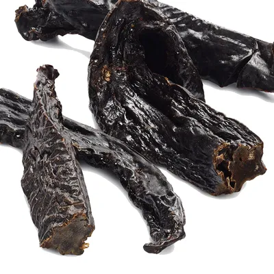 Suszone, ciemne kawałki przysmaku dla zwierząt o nieregularnym kształcie, bez widocznych opakowań ani oznaczeń marki.
