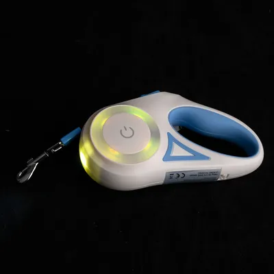 Witte en blauwe hondenriem met LED-licht, aan/uit-schakelaar symbool, metalen clip en CE-markering.