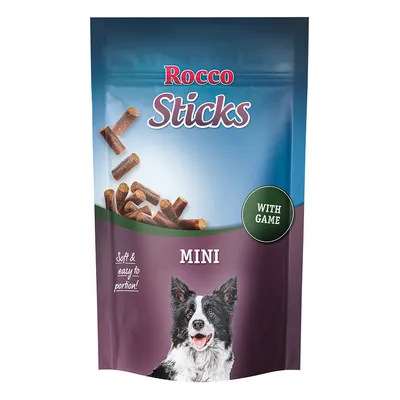 Rocco Sticks Mini, mehki in enostavno porcijski pasji prigrizki z divjačino. Embalaža prikazuje črno-belega psa in koščke prigrizka.