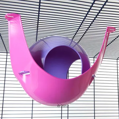 Pink and purple plastic hanging hideout attached to metal cage bars, spherical shape with open entrance visible.
