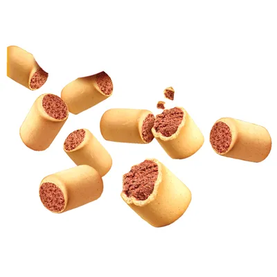 Flera cylinderformade hundgodisbitar med ljust yttre och mörkare fyllning, några hela och några brutna, synliga mot vit bakgrund.