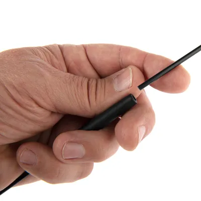 Ręka trzyma czarny, cienki kabel z wtyczką. Zbliżenie na połączenie między kablem a wtyczką.