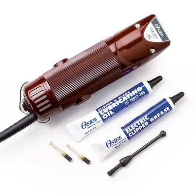 Tondeuse électrique Oster Golden A5 avec tube d’huile lubrifiante, graisse pour tondeuse, deux ressorts de rechange et une petite brosse de nettoyage visibles.