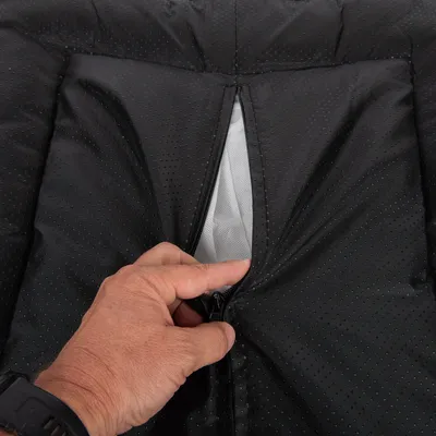 Nahaufnahme eines schwarzen, perforierten Stoffes mit Reissverschluss, der von einer Hand geöffnet wird. Sichtbar ist ein weisses Innenfutter.