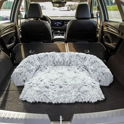 Graues, flauschiges Haustierbett auf der Ladefläche eines Autos, geeignet für Reisen oder Transport.