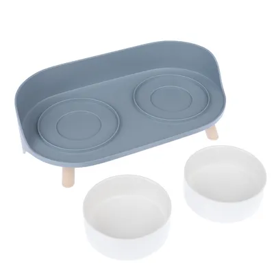 Conjunto de taças com suporte elevado azul e duas taças de cerâmica brancas, adequado para comida ou água.