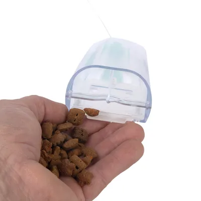 Mano che tiene un distributore di cibo che eroga crocchette. Adatto per il razioni consigliate preciso degli alimenti per animali.