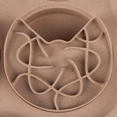 Round feeding maze made of beige plastic with cat head design and winding tracks for slow feeding.