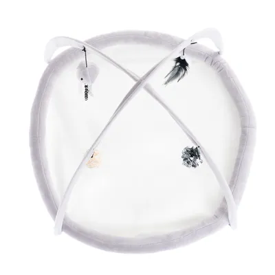 Tapis de jeu rond en tissu gris et blanc avec deux arches croisées, quatre jouets suspendus visibles : peluche grise, plume noire, balle en osier, boule brillante argentée.