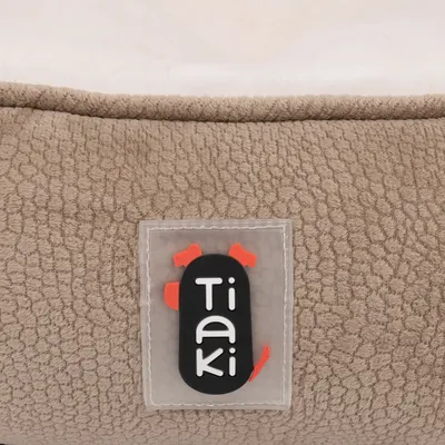 Tiaki-Logo auf einem beigen Stoff mit strukturierter Oberfläche und weissem Innenfutter sichtbar.