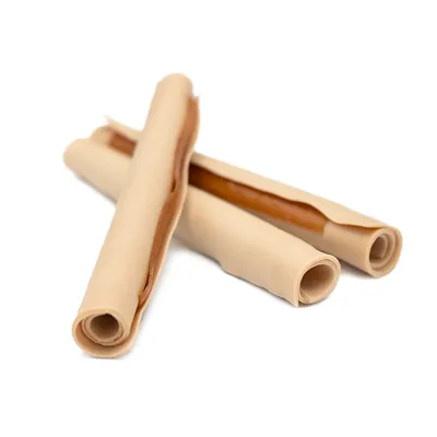 Três rolos de mastigar para cães enrolados, com camadas clara e castanha, visíveis sobre fundo branco.