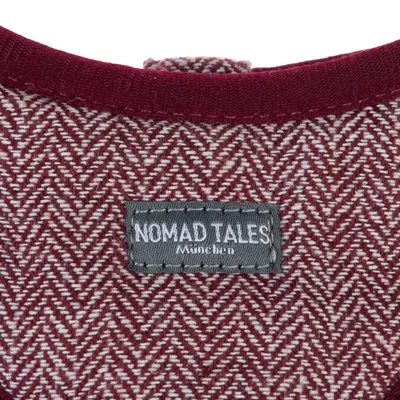 Nomad Tales München. Label auf rotem Stoff mit Fischgrätenmuster.