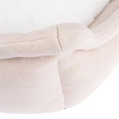 Close-up van beige, gewatteerde stof met witte binnenkant, mogelijk onderdeel van een huisdierenbed of vergelijkbare bekleding.