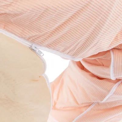 Detailní záběr na béžově pruhovaný látkový potah se zipem a pod ním polstrovaný materiál.