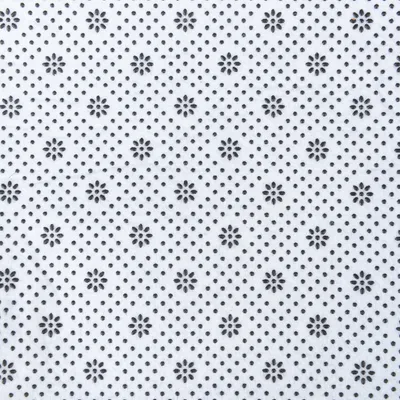 Surface en tissu blanc avec motif de points et fleurs noires, vue rapprochée du matériau. Aucun texte ou marque visible.