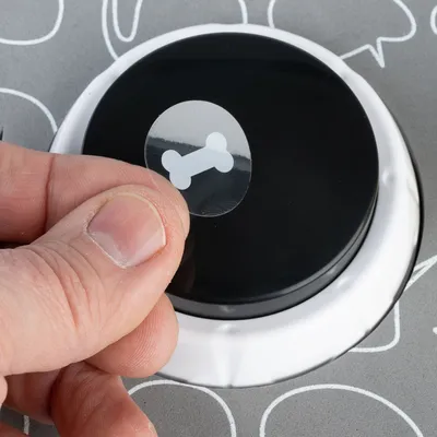 Mâna lipește un autocolant transparent cu simbol de os pe o tastă neagră. Utilizare produs pentru personalizare.