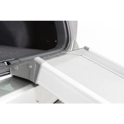 Aluminiowa rampa prowadząca do bagażnika samochodu, widoczna powierzchnia antypoślizgowa i metalowe krawędzie.