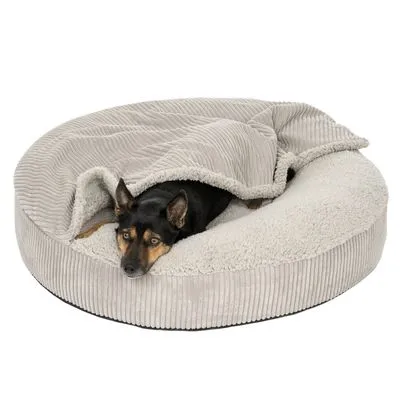 Hond liggend in een rond, lichtgrijs hondenbed met opstaande rand en zachte fleece bekleding, deels bedekt met een geribbelde deken.