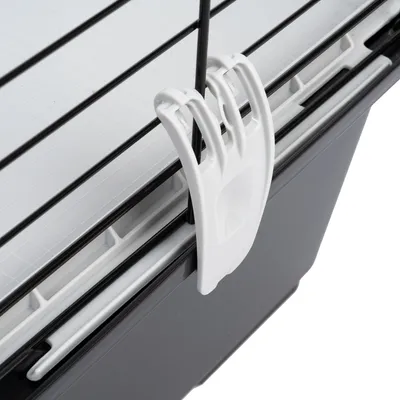 Detailaufnahme eines weissen Clips zur Befestigung an einem schwarzen Metallgitter und einer grauen Kunststoffwanne.