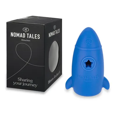 Nomad Tales München Bloom Rocket S, sininen raketinmuotoinen lelu pakkauksessa. Teksti pakkauksessa: Sharing your journey.